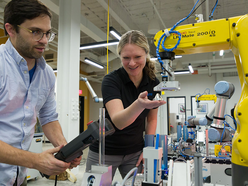 Francis Cartieri, CCAC Assistant Professor of Mechatronics, Entrepreneurial Manufacturing with Laura Kubiak from Toledo Public Schools during the NC3 Training event held at CCAC’s new Center for Education, Innovation & Training. Professor Cartieri is demonstrating the process of programming a robot to use an optical sensor to distinguish between different workpiece shapes to automate a typical package sorting task. 