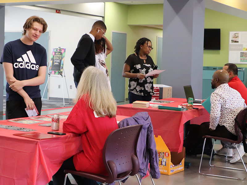 CCAC staff welcome students to an Open House event with informational signs and booths. 